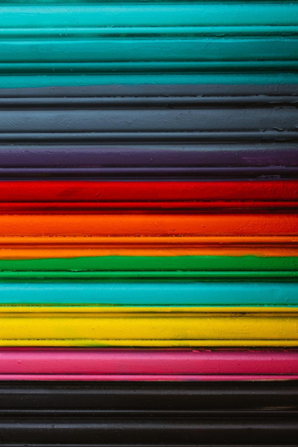 Colorful horizontal stripes of painted architectural molding in bright teal, red, orange, yellow, pink, and black.